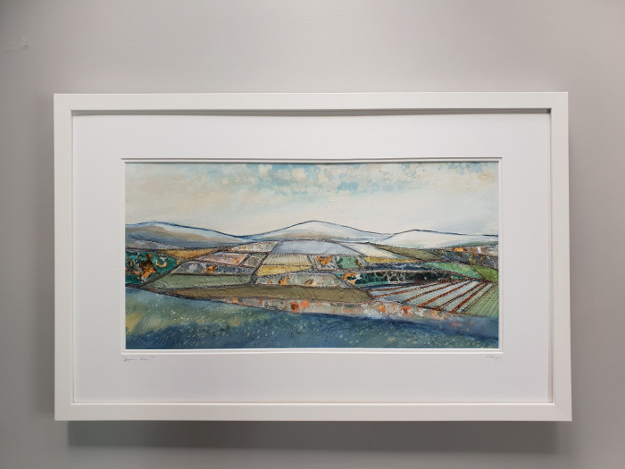 Landscape textile art piece in landscape of The Sperrin mountains.  The mountains meet with the sky.  The piece is browns, blues and greens.