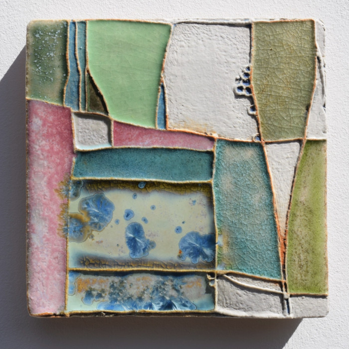 A layered stoneware wall panel with richly coloured slips and glazes