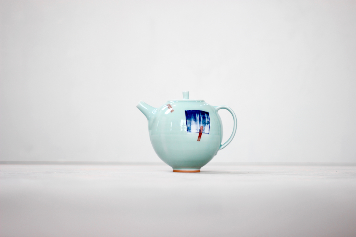 4 cup porcelain teapot with orange foot. Blue wash square pattern with red dashes, fired
with a celadon (greeny blue) glaze.